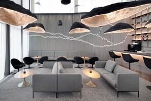 A modern lounge area with sofas, tables, and pendant lighting.