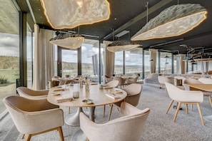 Un comedor moderno con mesas redondas, sillas cómodas e iluminación colgante.