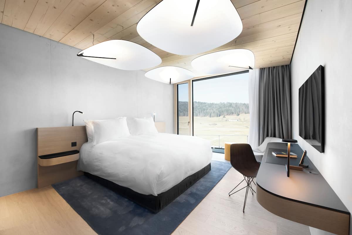 Une chambre moderne avec un grand lit, un bureau et une télévision.
