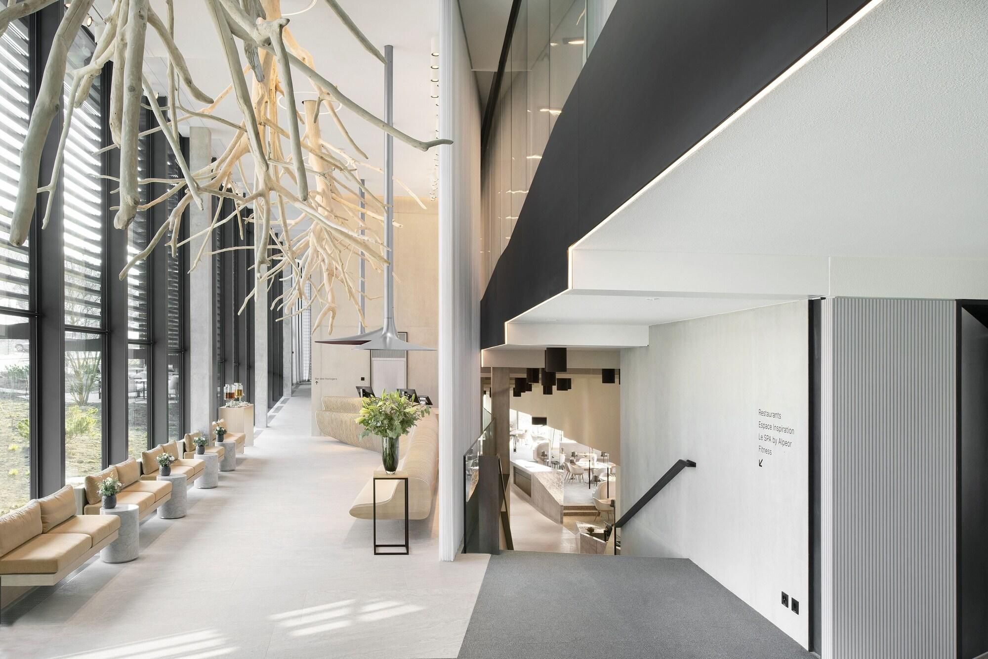 A modern interior with a long bench seating area, a staircase, and a reception desk.