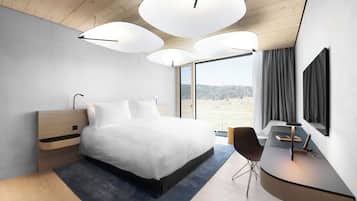 A modern bedroom with a large bed, a desk, and a TV.