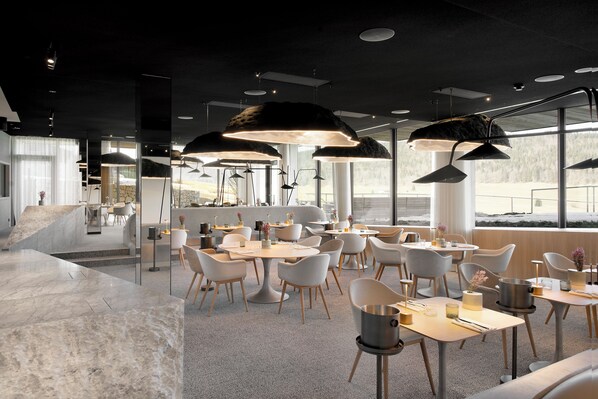 A modern restaurant with marble flooring, white chairs, and pendant lighting.