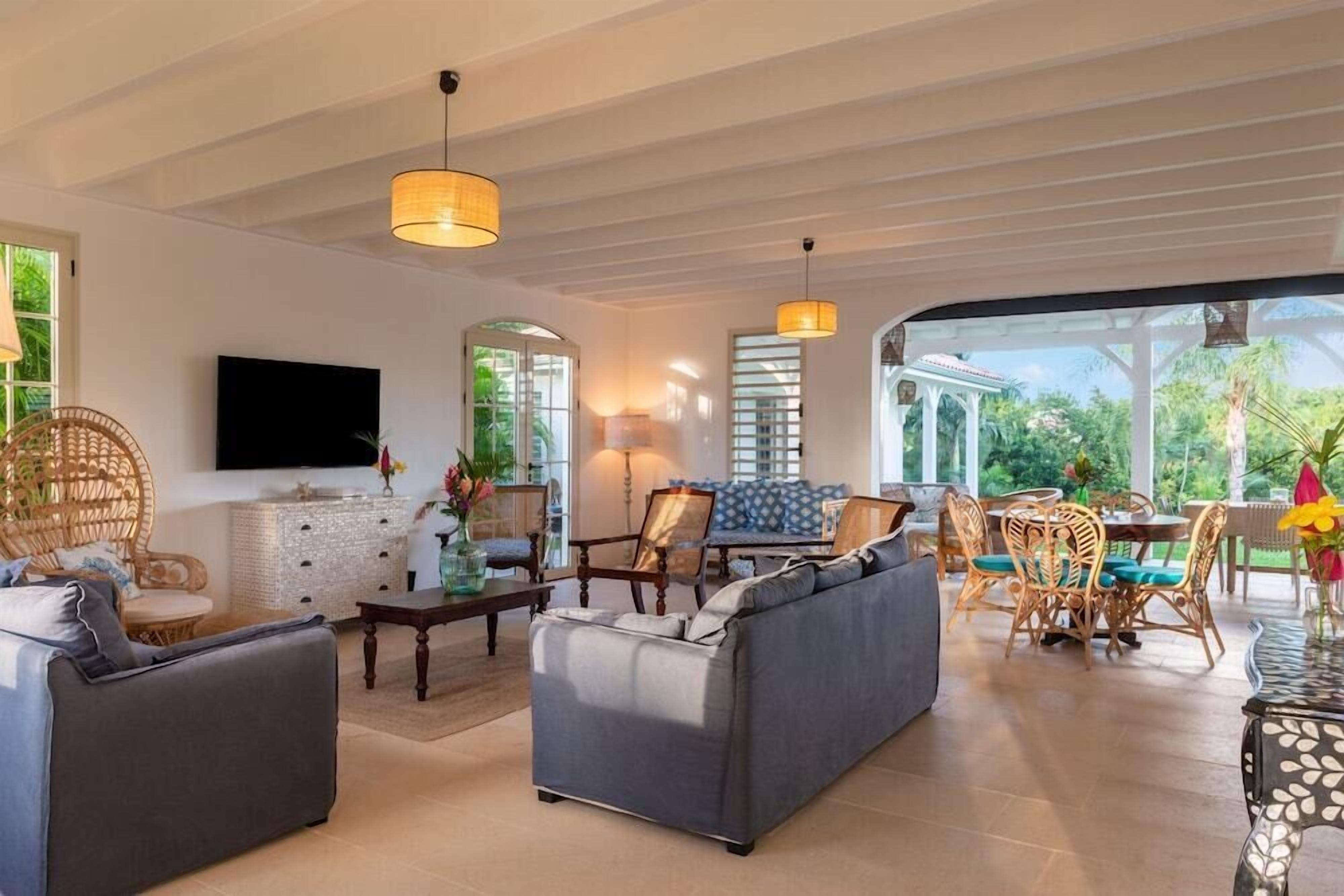 Un amplio espacio de sala con sofá, sillas, mesa de comedor y televisor.