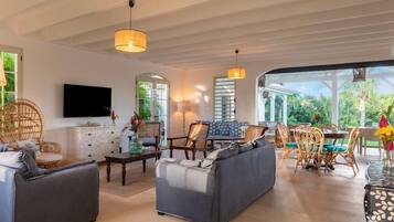 Un amplio espacio de sala con sofá, sillas, mesa de comedor y televisor.