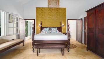 A bedroom with a four-poster bed, a bench, a large mirror, and a wardrobe.