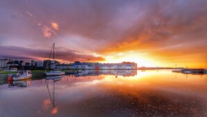 A calm waterfront with boats docked, buildings in the background, and a sunset reflecting on the water. - Clarin Rest, luxury private room, Clarinbridge Wild Atlantic Way, Galway. (Co Galway)