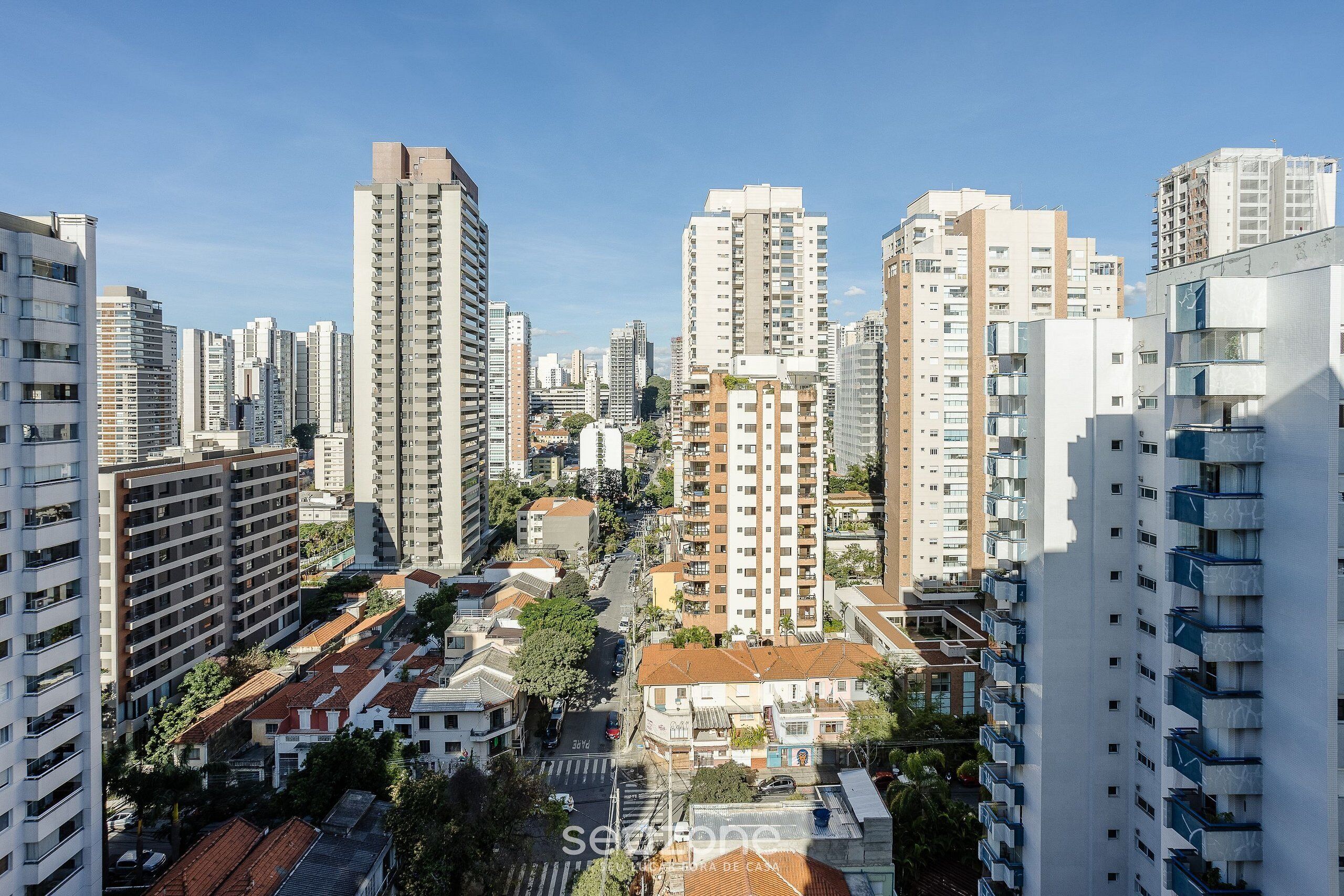 Un immeuble résidentiel de grande hauteur, doté de nombreux balcons, d’une cour intérieure et offrant une vue dégagée sur le ciel.