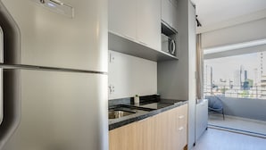 Una cocina moderna con electrodomésticos de acero inoxidable, una encimera negra y armarios de madera. Hay una pequeña planta en maceta sobre la encimera.
