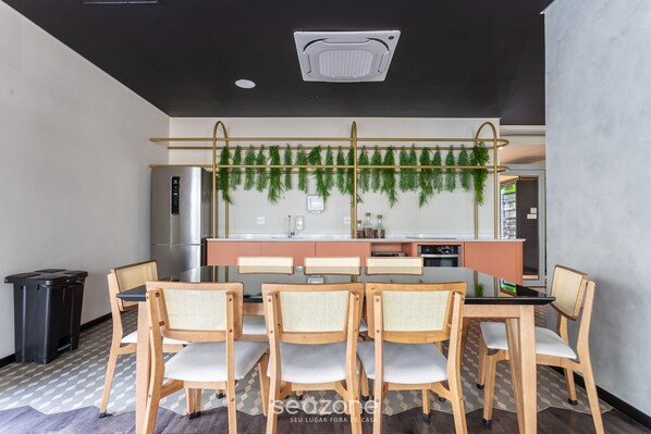A modern kitchen with a central island, wooden chairs, and a hanging plant decoration.