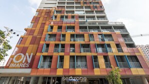 Un immeuble à plusieurs étages, doté d’une façade colorée, de balcons et d’une enseigne indiquant « ON IMARES ».