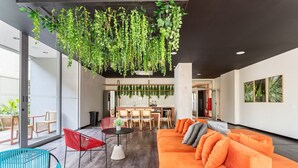 Un intérieur moderne avec un canapé, des fauteuils, un coin repas et des plantes suspendues.