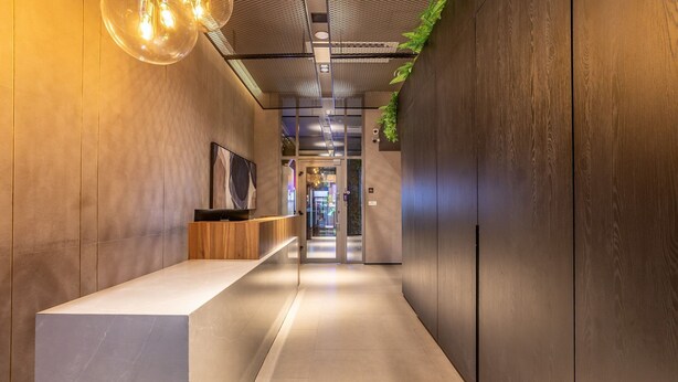 A modern hallway with a reception desk, a large artwork, and a ceiling with a grid pattern.