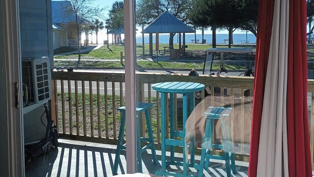 A room with a large sliding glass door leading to an outdoor deck with a gazebo, chairs, and a view of a body of water.