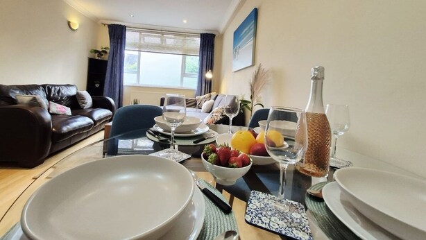 A dining area with a table set for four, including plates, glasses, and a bowl of fruit. - Stylish London FLAT near Highgate tube station (London)