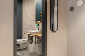 Un baño moderno con inodoro, lavamanos y espejo.
