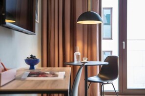 Una habitación moderna con una mesa de madera, una silla negra, un tazón azul, una botella de vidrio y una lámpara colgante negra.
