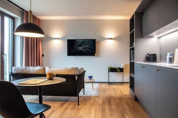 Une cuisine moderne avec des meubles de couleur grise, un coin repas avec une table ronde et des chaises, et un canapé.