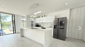 A modern kitchen with a central island, stainless steel appliances, and a large sliding door to a patio area.