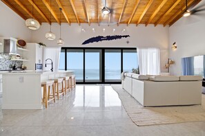 A modern kitchen with a large island, bar stools, and a view of the sea through large windows. - Oceanfront Villa w/ Infinity Pool, 2 Casitas w/ Plunge Pools, Dock, Concierge (Punta Blanca)