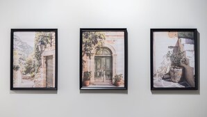 Tres obras de arte enmarcadas que muestran escenas campestres con puertas, plantas y paredes de piedra.