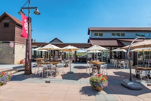 An outdoor patio area with tables and chairs, surrounded by potted plants and umbrellas. - Steps to Park City Mtn Lift, Pool + Hot Tub, Dog Friendly, Walk to Cafe (Park City)