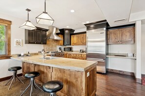 A modern kitchen with a central island, stainless steel appliances, wooden cabinets, and pendant lighting. - Steps to Park City Mtn Lift, Pool + Hot Tub, Dog Friendly, Walk to Cafe (Park City)
