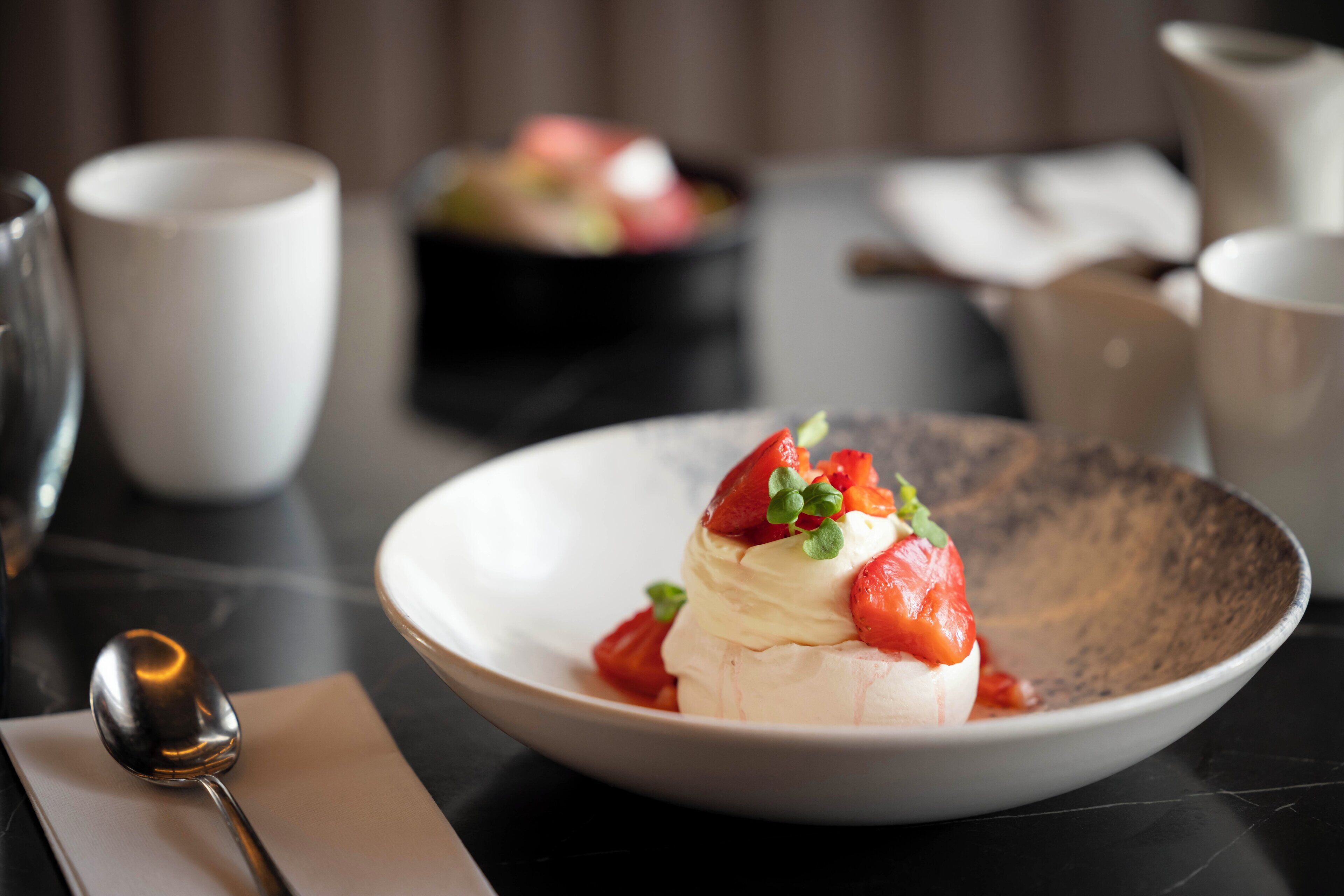 A dessert on a plate with strawberries and mint leaves.