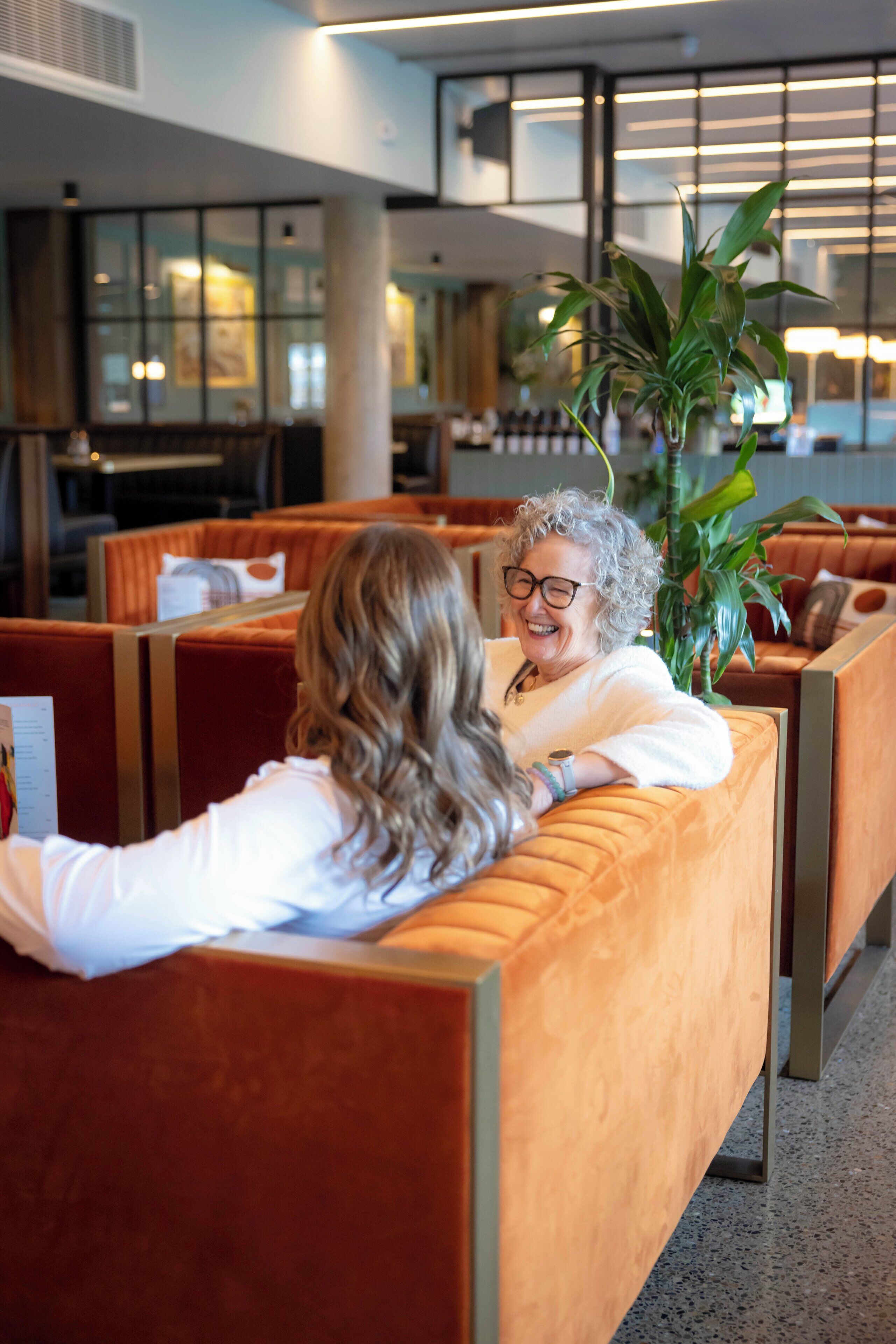A hotel lobby with seating areas, a large plant, and a modern interior design.