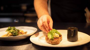 A chef placing a leaf on a food item on a plate.