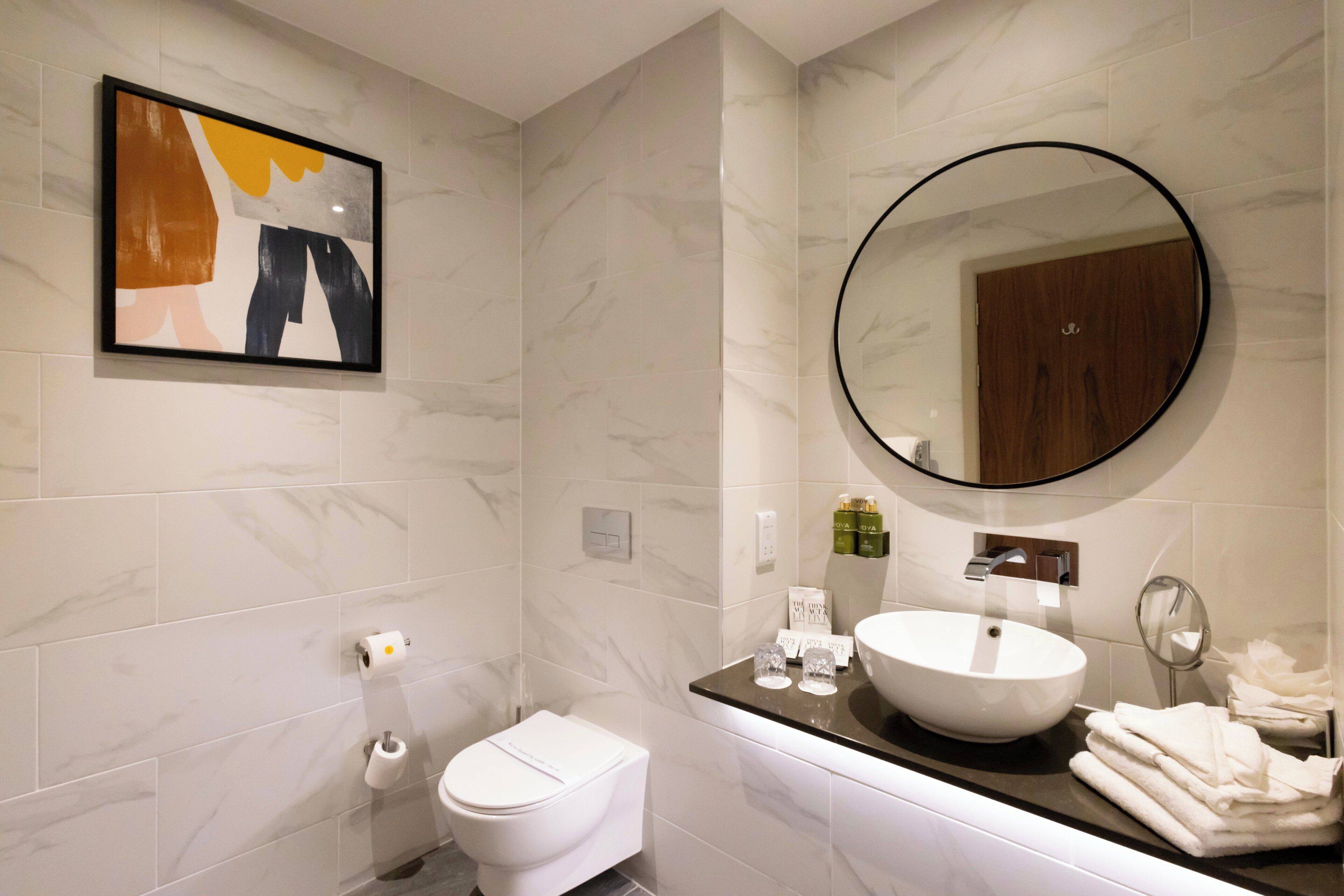 Une salle de bain moderne avec des toilettes, un lavabo et un miroir.