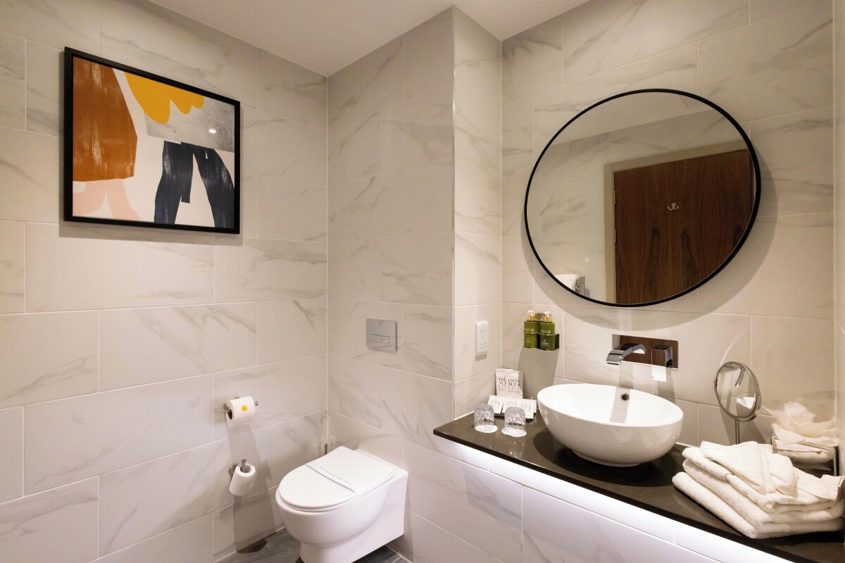 A modern bathroom with a toilet, sink, and mirror.