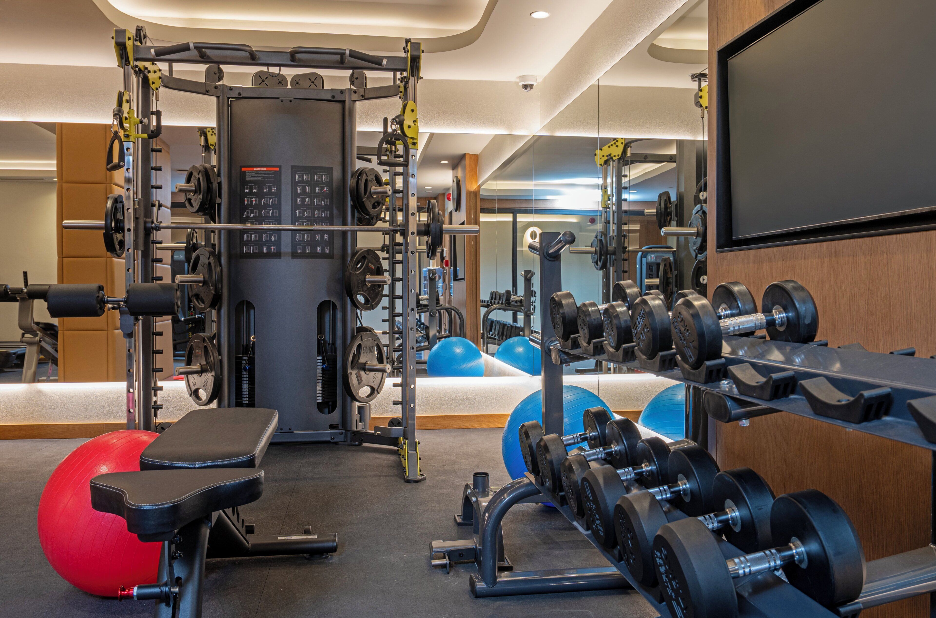 A gym with weightlifting equipment, exercise balls, and a bench.