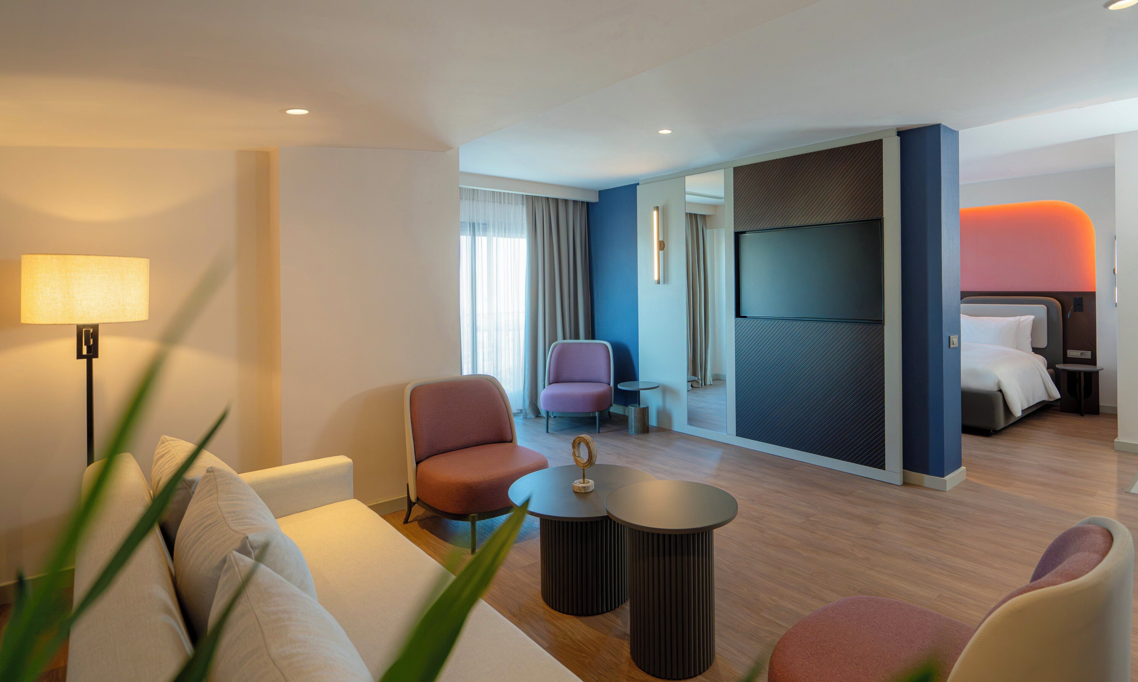 Una moderna camera d'albergo con un divano, poltrone, un tavolino, una TV e un letto.
