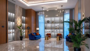 A modern lobby with marble flooring, blue sofas, and a variety of decorative items on shelves.