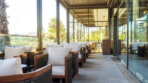 A covered outdoor seating area with wicker chairs and a glass wall.
