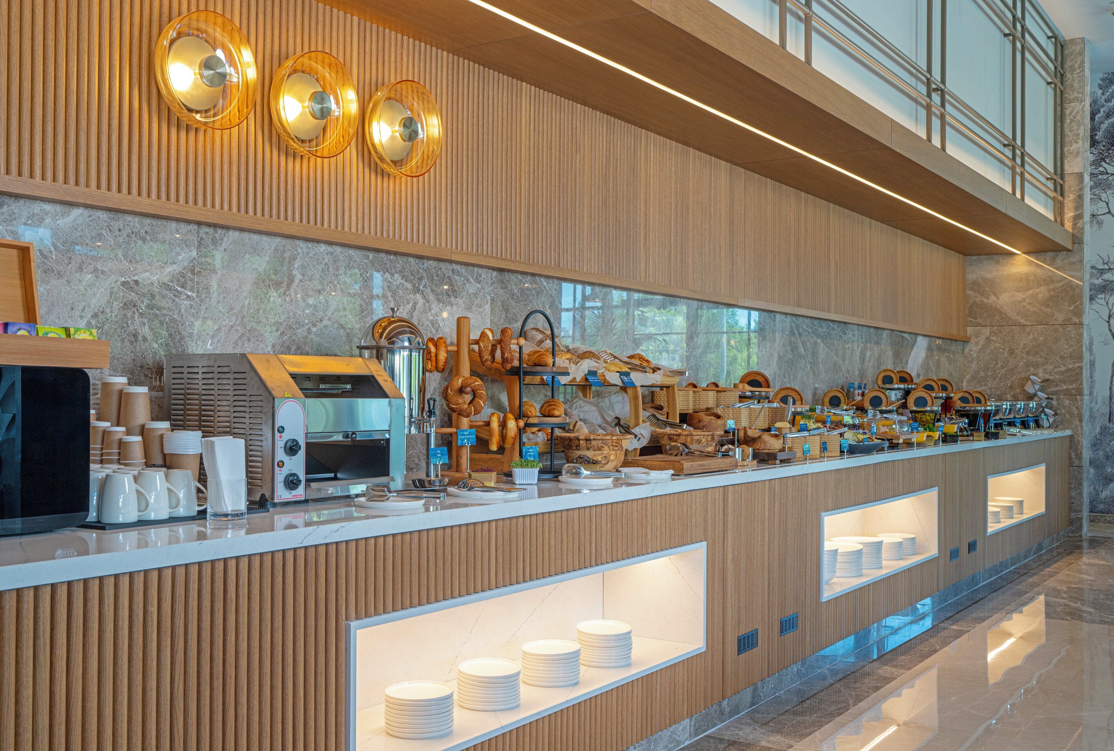 A buffet counter with a variety of food items, a coffee machine, and a cash register.