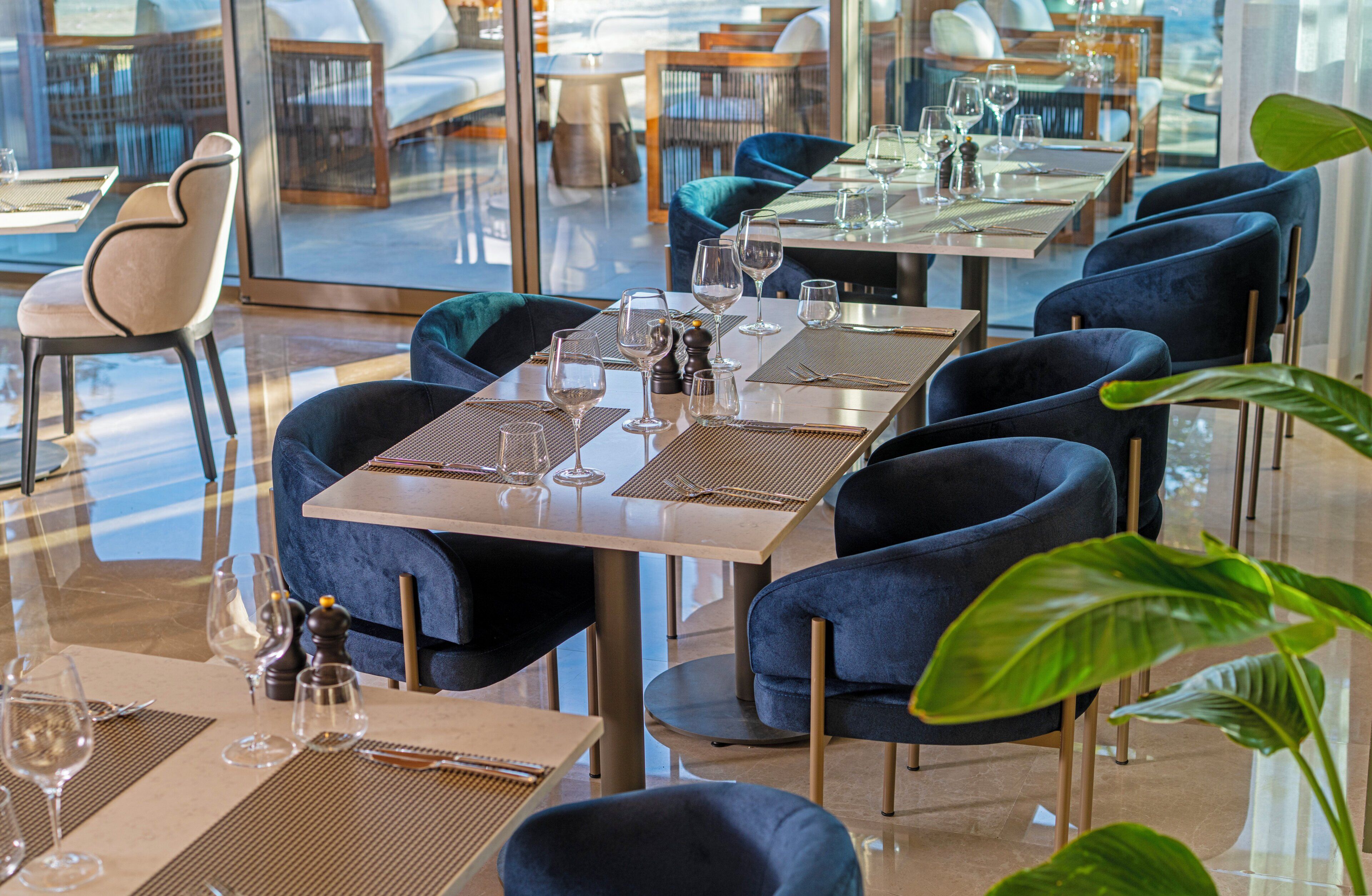 A restaurant with tables set for dining, chairs, and a large window offering a view.