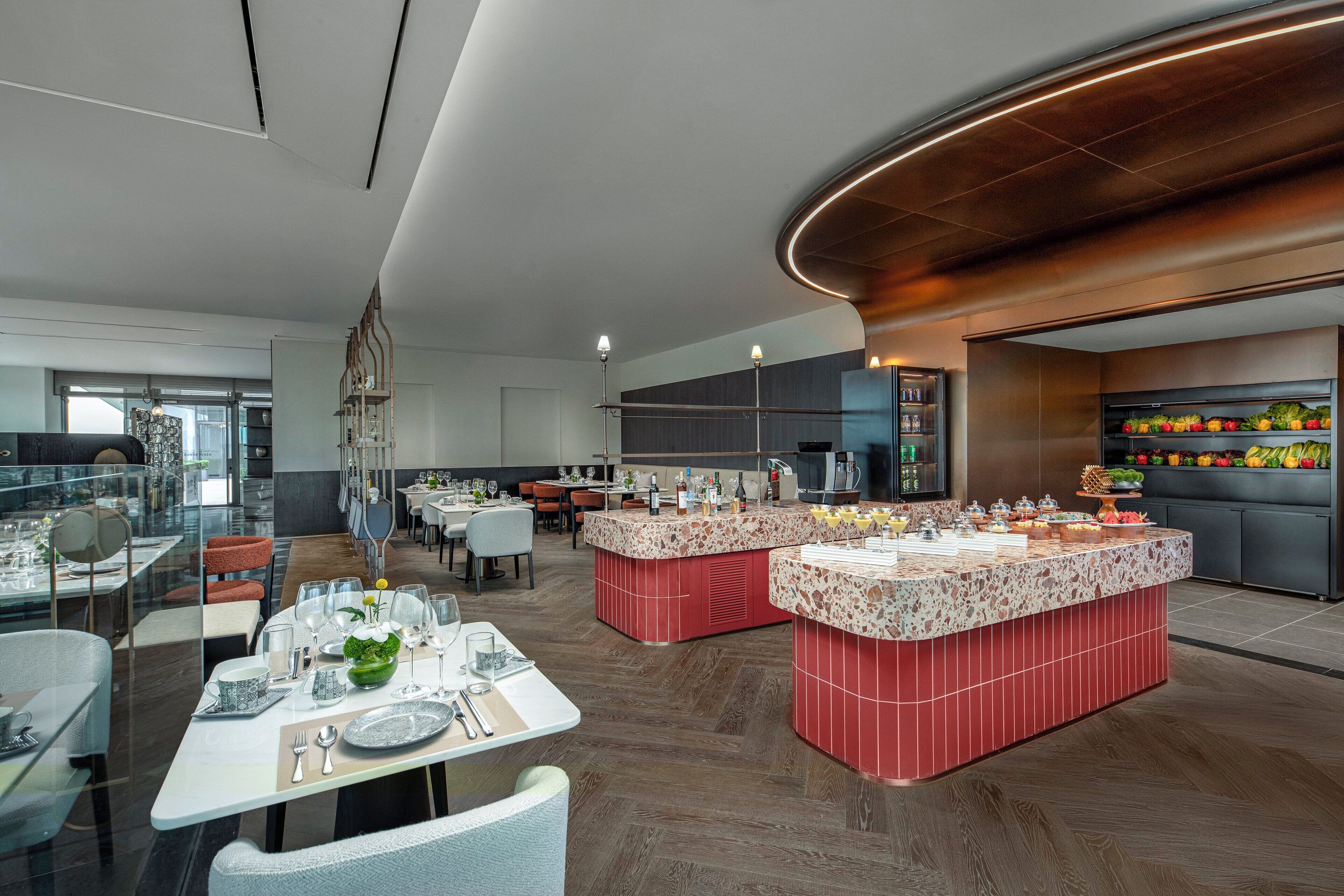 Un ristorante moderno con un'isola centrale, tavoli da pranzo e un angolo cottura.