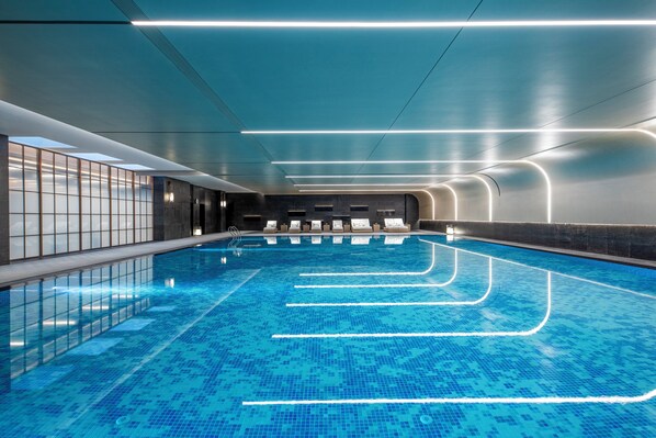 Une piscine intérieure moderne, dotée de lignes de nage clairement délimitées et d’un éclairage contemporain.