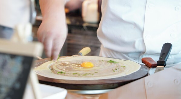 Un chef préparant un plat sur une plaque de cuisson chaude.