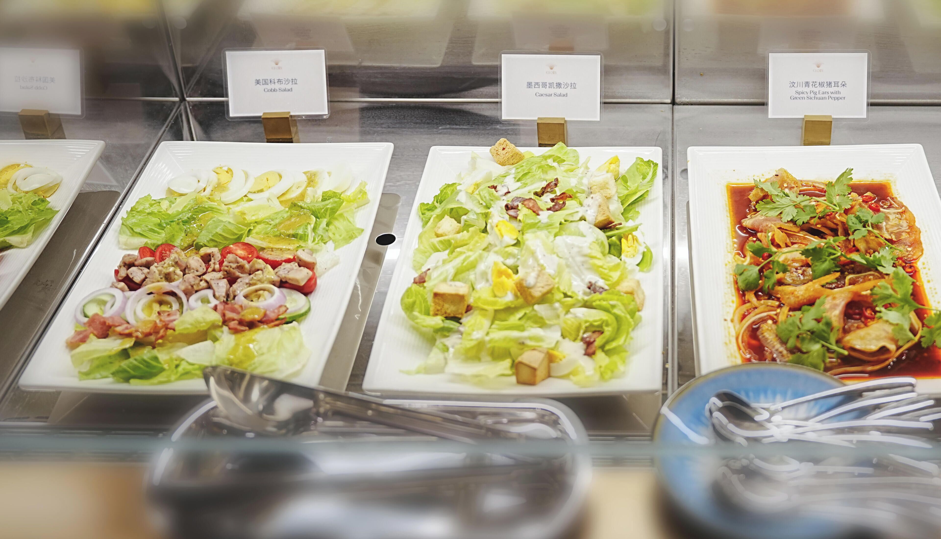 A buffet with various dishes including salads and a spicy dish.