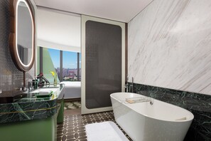 Une salle de bain moderne avec une baignoire, un grand miroir et une vue sur la ville.