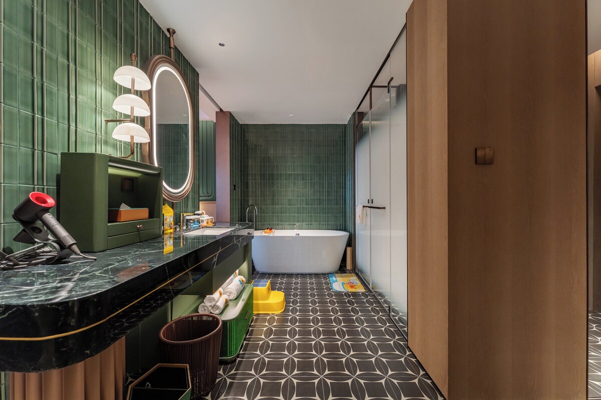 Un baño moderno con encimera de mármol, una bañera independiente, un espejo grande con iluminación y un suelo estampado.