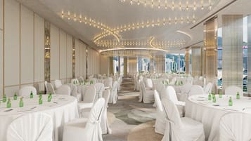 A spacious banquet hall with round tables, white chairs, and green bottles.