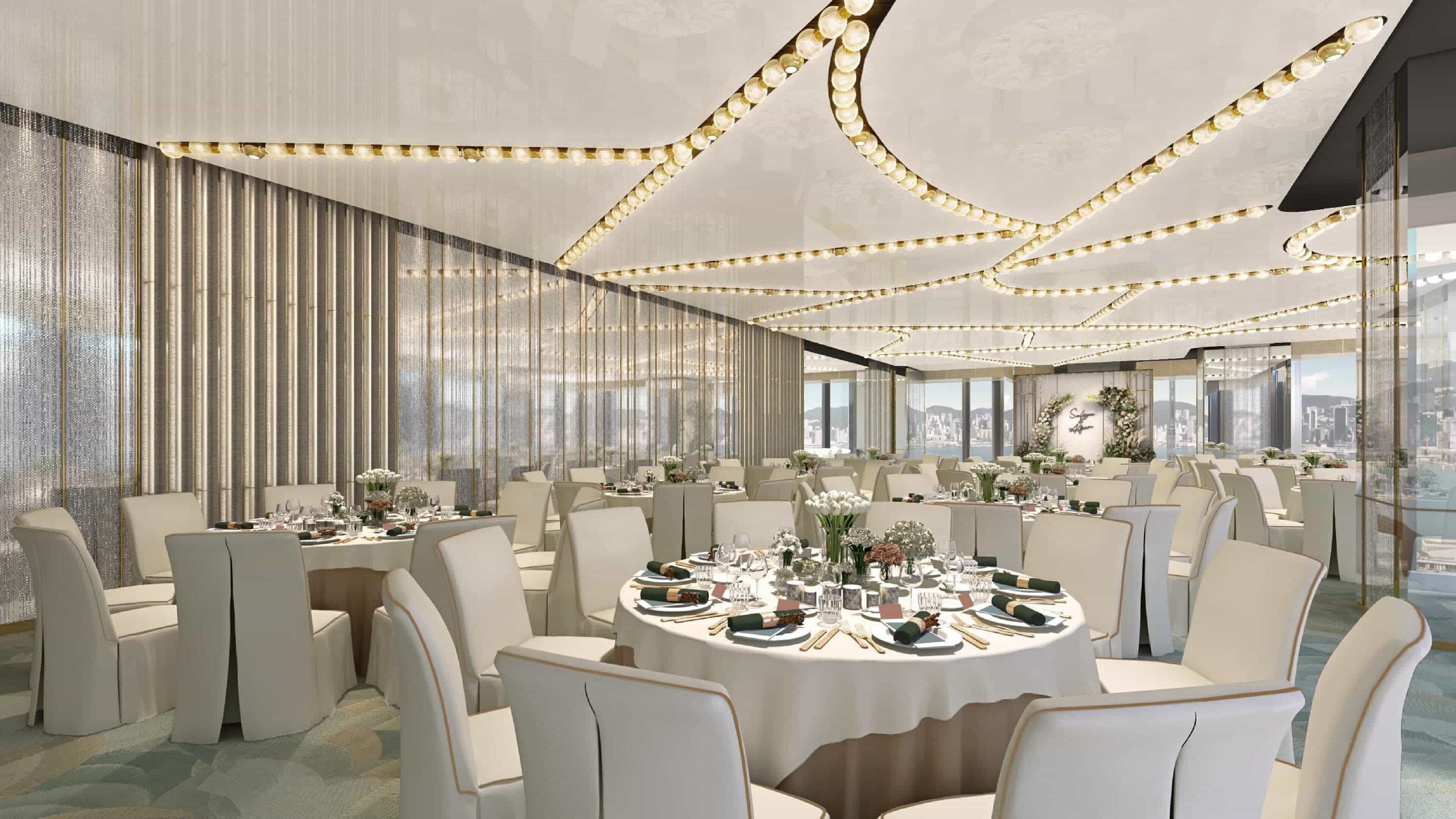 Un comedor amplio y elegantemente decorado con mesas redondas, sillas blancas y luces colgantes.