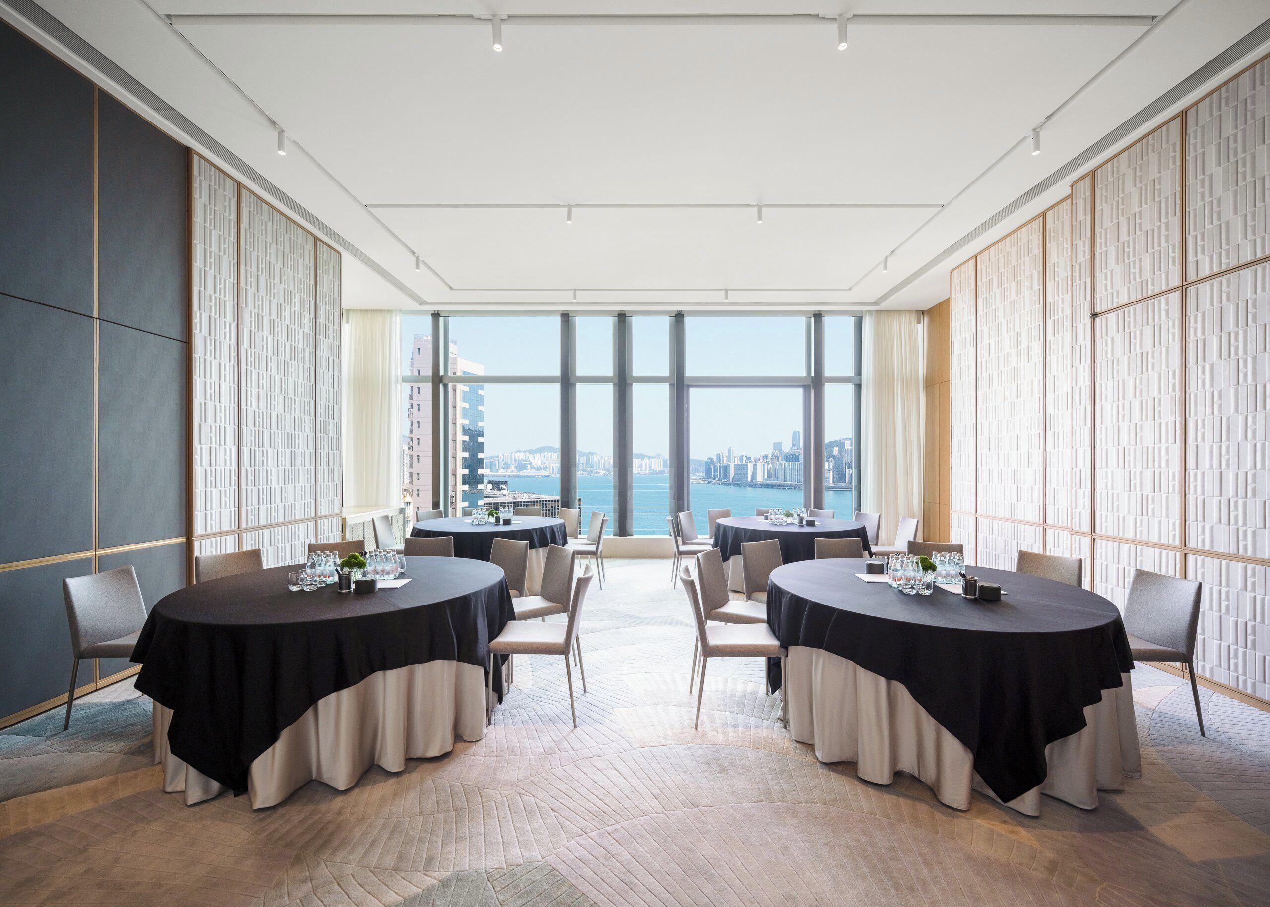 A conference room with two round tables, large windows with a city view, and a modern interior design.