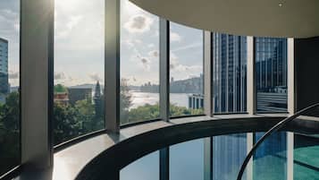 A modern interior with large windows offering views of a cityscape and a river.
