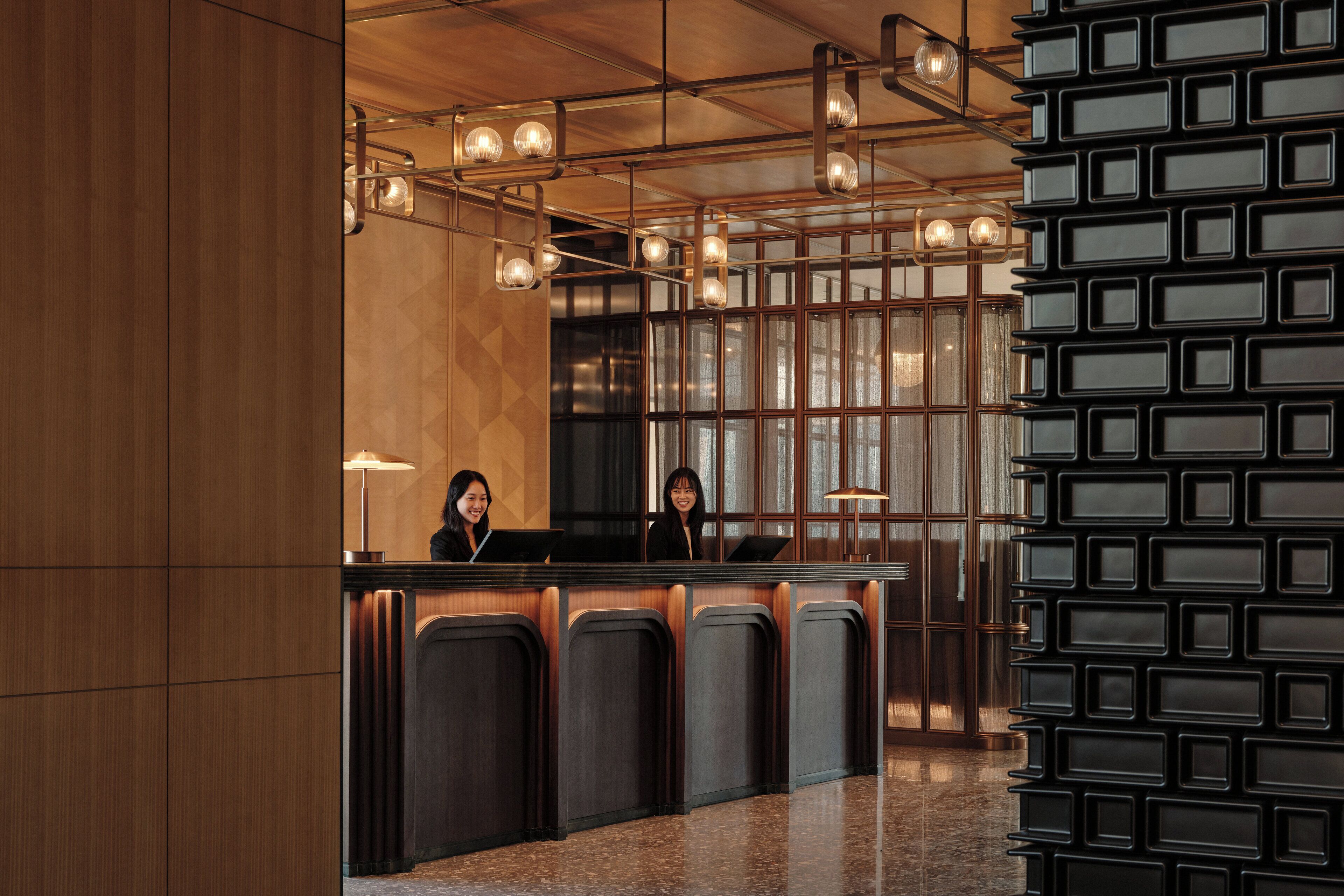 A reception desk with a modern design, featuring a wooden panel and a black wall with rectangular panels.