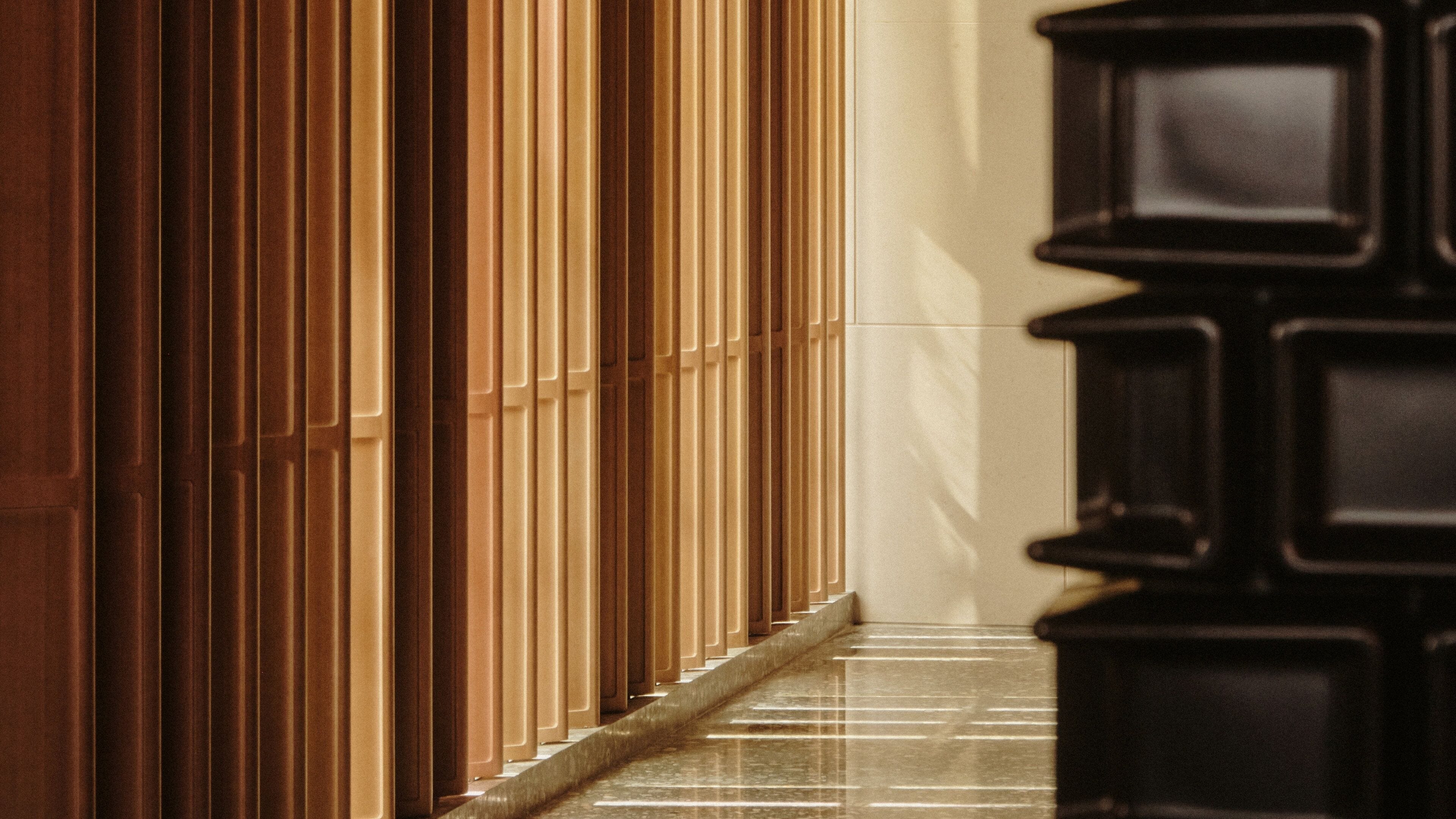 A corridor with a series of vertical wooden panels and a tiled floor.