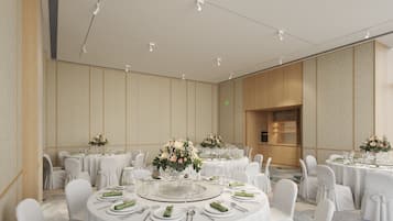 A spacious banquet hall with round tables set for dining, featuring white tablecloths and green napkins.